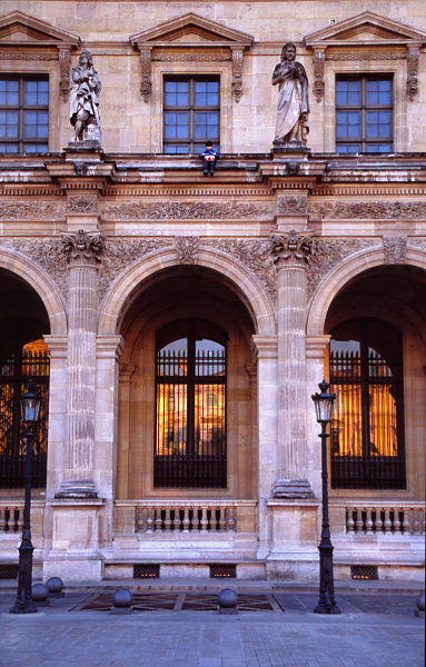 The Louvre in the evening, the little boy sits precariously under a window.